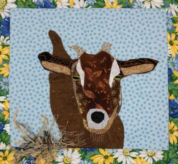closeup of brown goat and fabric hay on fabric wall hanging art piece