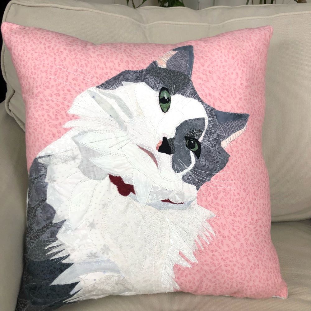 Fabric pet picture of grey and white cat on a pink pillow on ivory chair