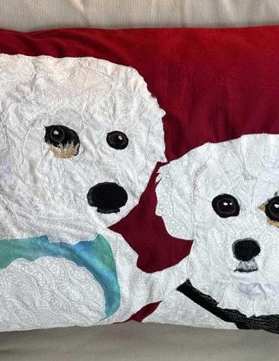 This two dog fabric pillow shows them both with their car harnesses on as they go for a car ride. The maroon background contrasts well with their white fur.