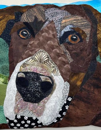 This fabric pet portrait pillow shows the face of a brown dog sitting outside in the grass